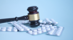 A judge’s gavel surrounded by medication tablets.