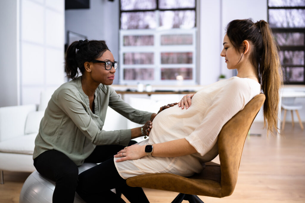 Peaceful Pregnant Woman Having A Relaxing Massage From Doula At Home